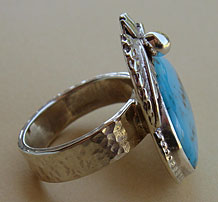 Cette bague américaine south western possède un anneau en argent martelé et est ornée d'une turquoise et de plumes d'aigle symbole américain