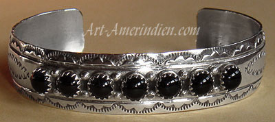 Ce bracelet tribal Navajo en argent massif est orné de sept onyx et de symboles ethniques indiens.